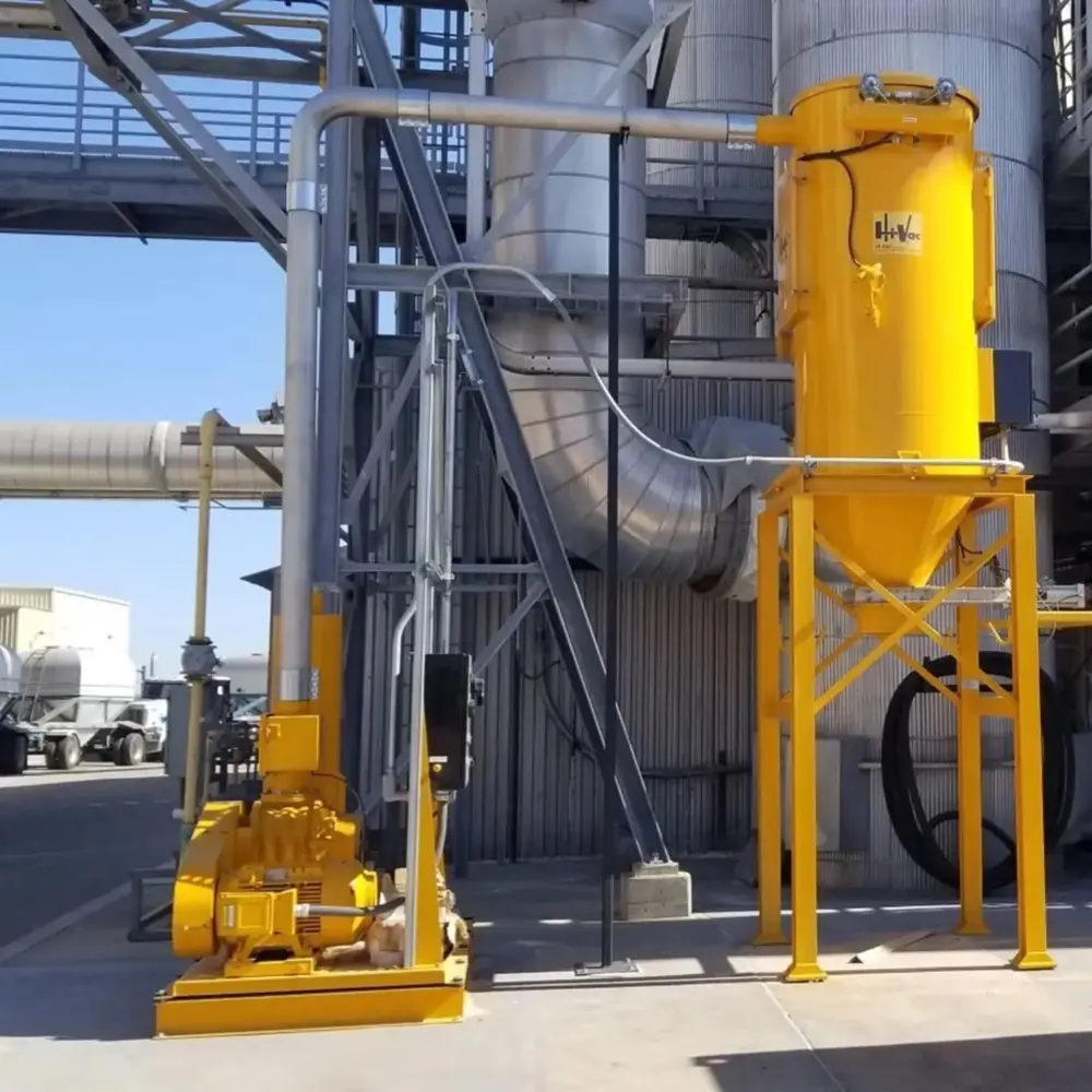 Bright yellow Hi-Vac industrial vacuum cyclone and blower skid with piping and support frame beside large metal ductwork.