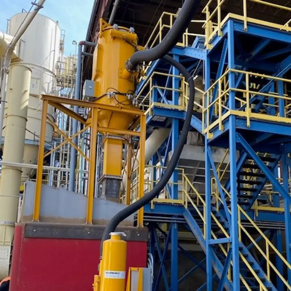 Yellow cyclone with black Hi-Vac hose on blue steel stairs and yellow railings — industrial vacuum equipment