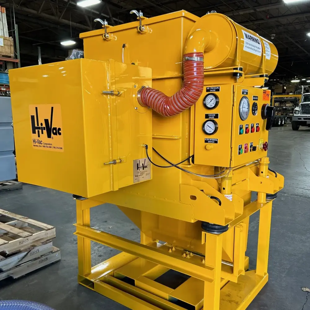 Hi-Vac yellow industrial vacuum unit with control panel, pressure and vacuum gauges and red corrugated hose in warehouse